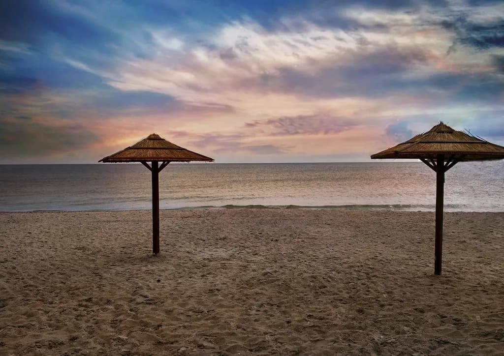 Serenity at Dusk: Tranquil Beachscape with Umbrellas and a Colorful Sky