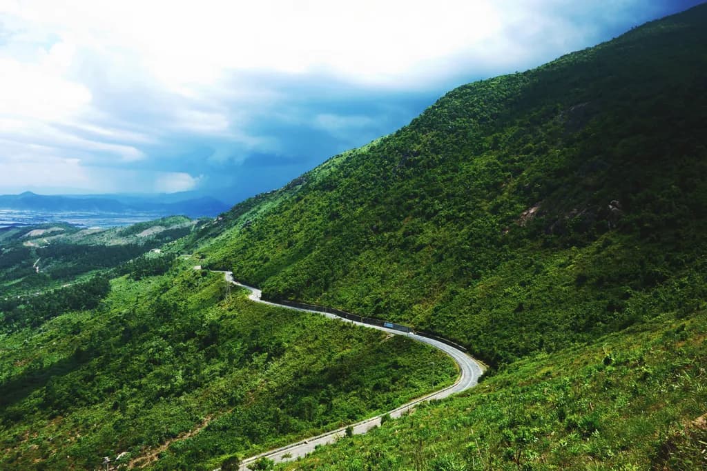 Whispers of the Winding Road: A Journey Through Lush Green Hills and Stormy Skies